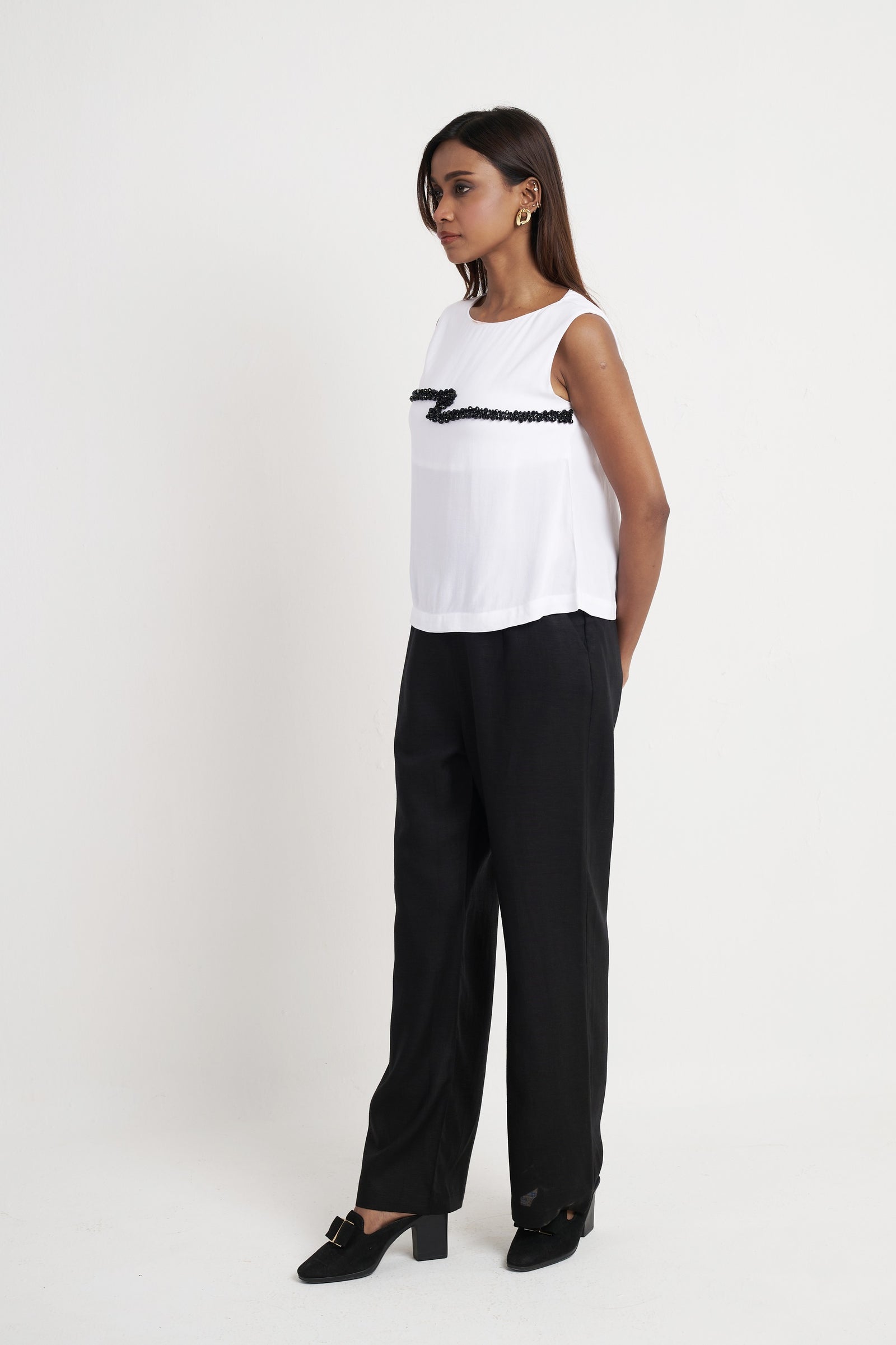 Beaded embroidered sleeveless top for women in bright white styled with black trousers