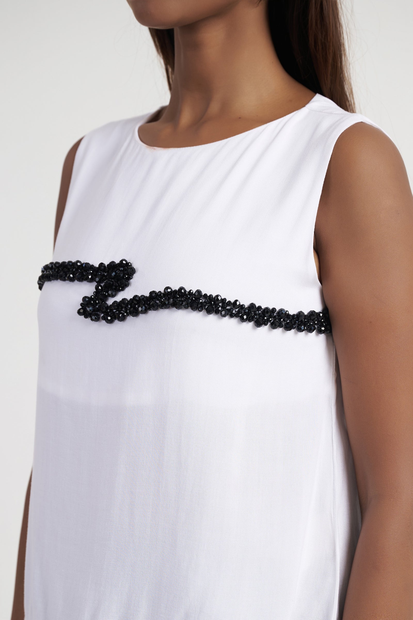 Close up of beaded cord embroidery on bright white sleeveless top